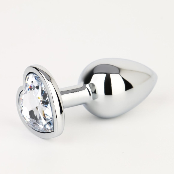 Серебристая анальная пробка с прозрачным кристаллом в форме сердца - 7 см. Серебристая анальная пробка с прозрачным кристаллом в форме сердца - 7 см.